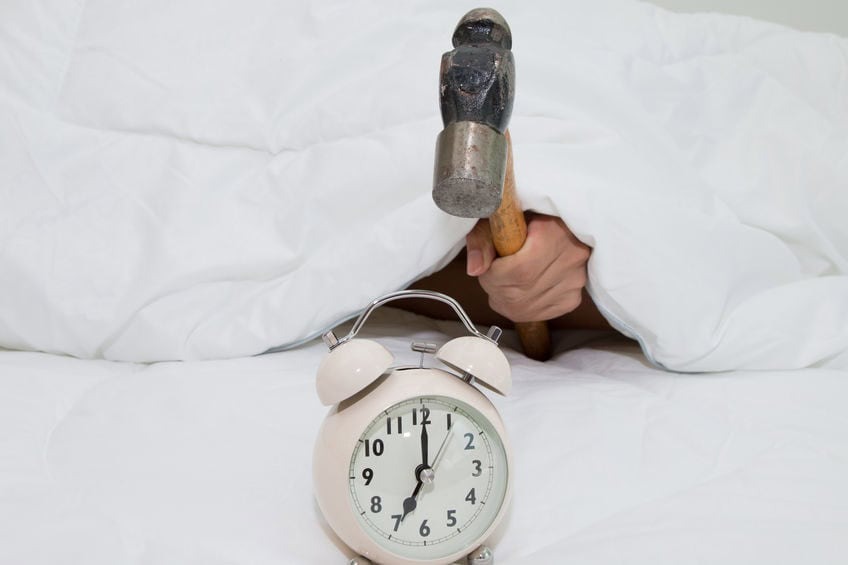 Closeup of a man with a hammer smashing alarm clock